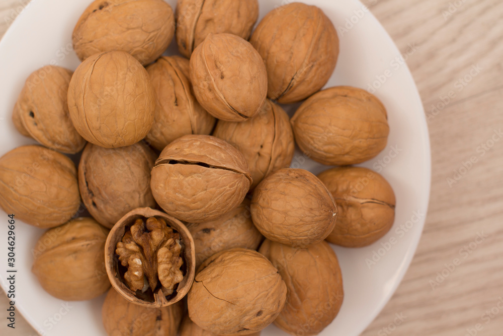walnuts on a white plate on a woodden table walnuts on a white plate on a woodden table