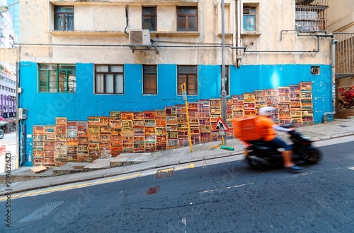 A motorcycle courier passing by the famous Graham Street Wall Mural, a colorful street art and a popular Instagram check-in spot in Central District, Hong Kong, China, Asia