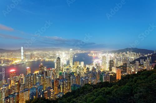 Night scenery of Hong Kong viewed from top of Victoria Peak with city skyline of crowded skyscrapers by Victoria Harbour   Kowloon area across the busy seaport   Cityscape of Hongkong in blue twilight