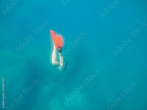 man in underwater in flippers looking at sea bottom