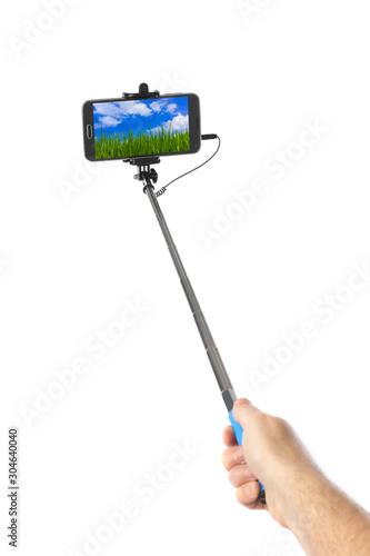 Hand with smartphone selfie stick and landscape (my photo)