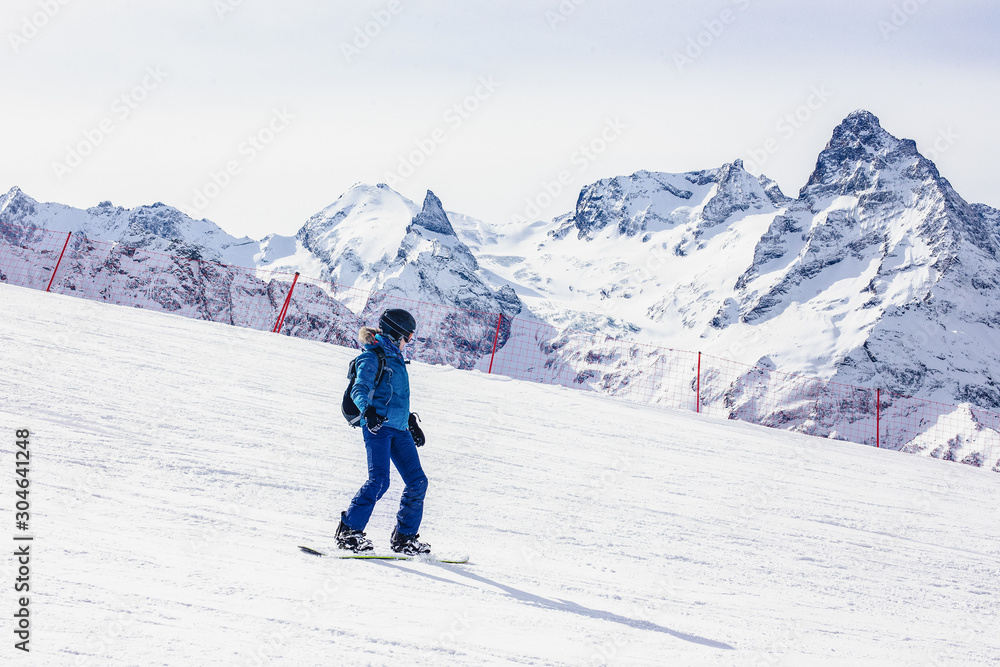 Young woman snowboarder on a background of mountains.