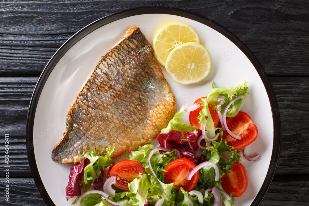 Main dish fried dorada fillet with vegetable salad close-up on a plate. Horizontal top view Main dish fried dorada fillet with vegetable salad close-up on a plate. Horizontal top view