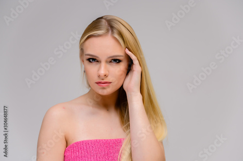 Beauty concept is a pretty model right in front of the camera. Close-up portrait of a beautiful blonde girl with excellent makeup with long smooth hair on a white background.