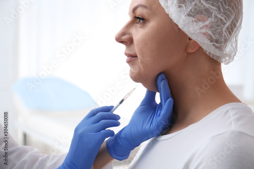 Mature woman with double chin receiving injection in clinic photo