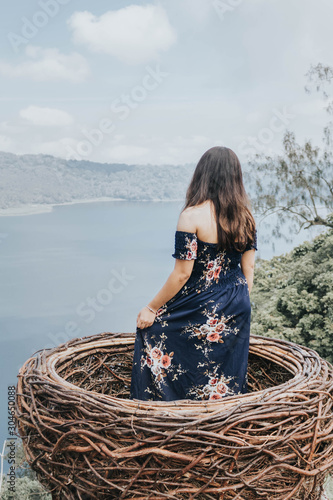 Pretty Asian woman is sitting on straw nest, Wanagiri hidden hill, Bali. photo