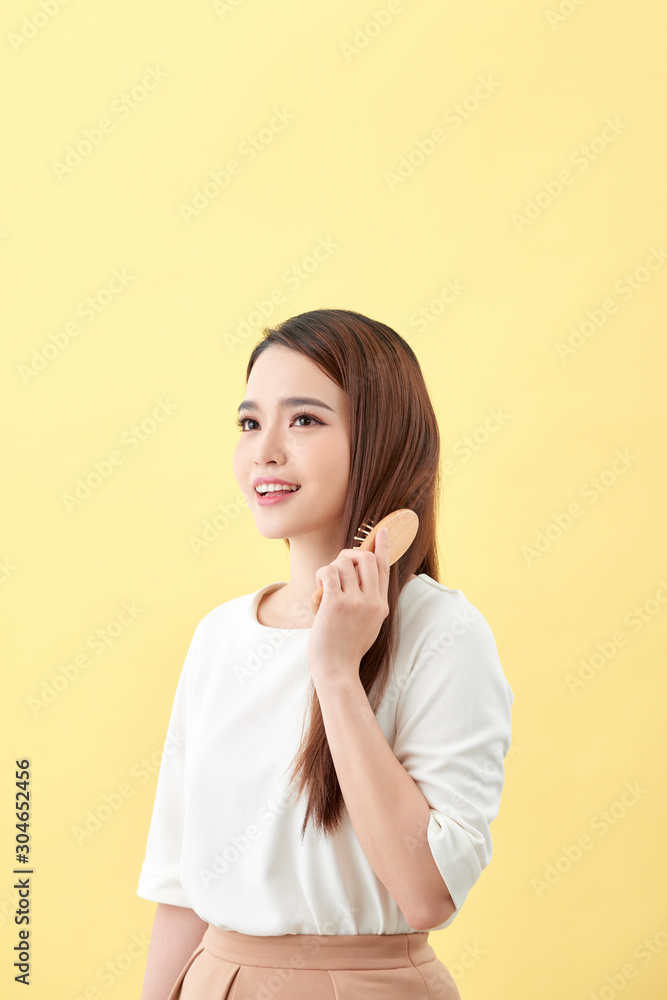 Portrait of beautiful young woman combing her hair and smiling Portrait of beautiful young woman combing her hair and smiling