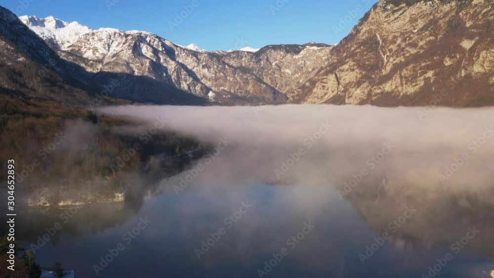 Flying over low fog covering lake in Slovenia viewing the mountains on sunny day. Flying over low fog covering lake in Slovenia viewing the mountains on sunny day.