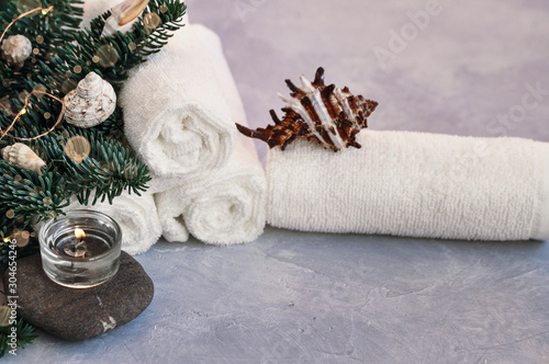Christmas and new year card with fir branches decorated with balls, lights, shells and stones for Spa treatments on a gray background