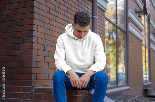Mockup white hoodie on a young man on the street, front view.