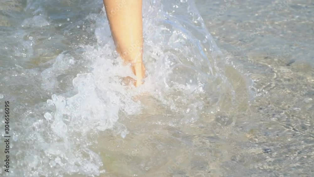 female legs walking in a shallow sea female legs walking in a shallow sea