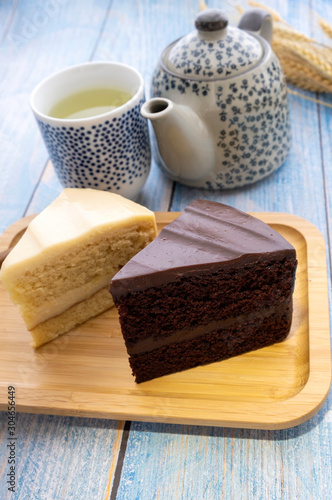 Hot tea with chocolate cake and milk cake on the blue wooden floor