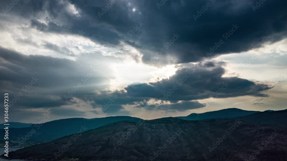 Godrays piercing through the dense clouds over the Hardanger fjord. Aerial view of one of the Norwegian fjords. Godrays piercing through the dense clouds over the Hardanger fjord. Aerial view of one of the Norwegian fjords.