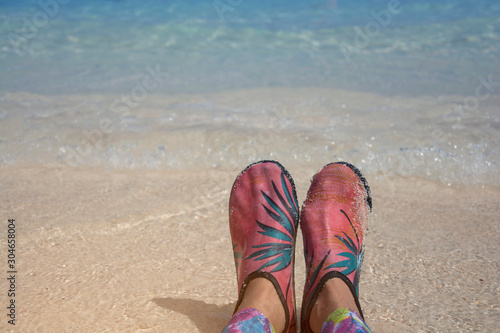 Wading shoes of woman legs on the beach in front of sea