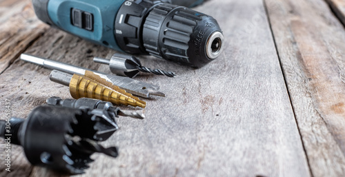 Variety of different types of bit drill with cordless drill displayed on old wooden background. Selective focus.