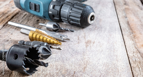 Variety of different types of bit drill with cordless drill displayed on old wooden background. Selective focus.