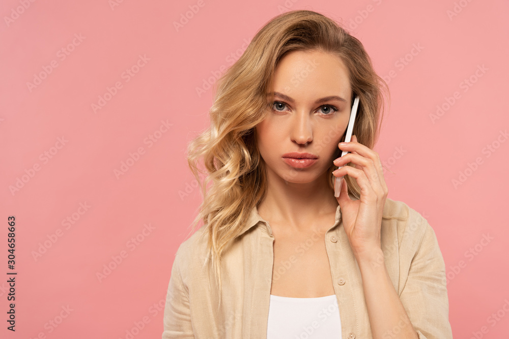 Serious blonde woman talking on smartphone isolated on pink Serious blonde woman talking on smartphone isolated on pink