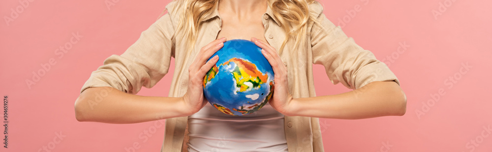 Cropped view of woman holding globe in hands isolated on pink, panoramic shot Cropped view of woman holding globe in hands isolated on pink, panoramic shot
