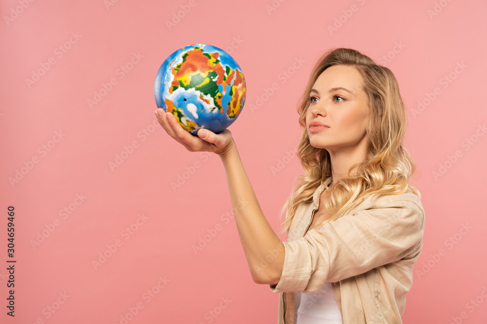 Blonde woman holding globe in hand isolated on pink Blonde woman holding globe in hand isolated on pink