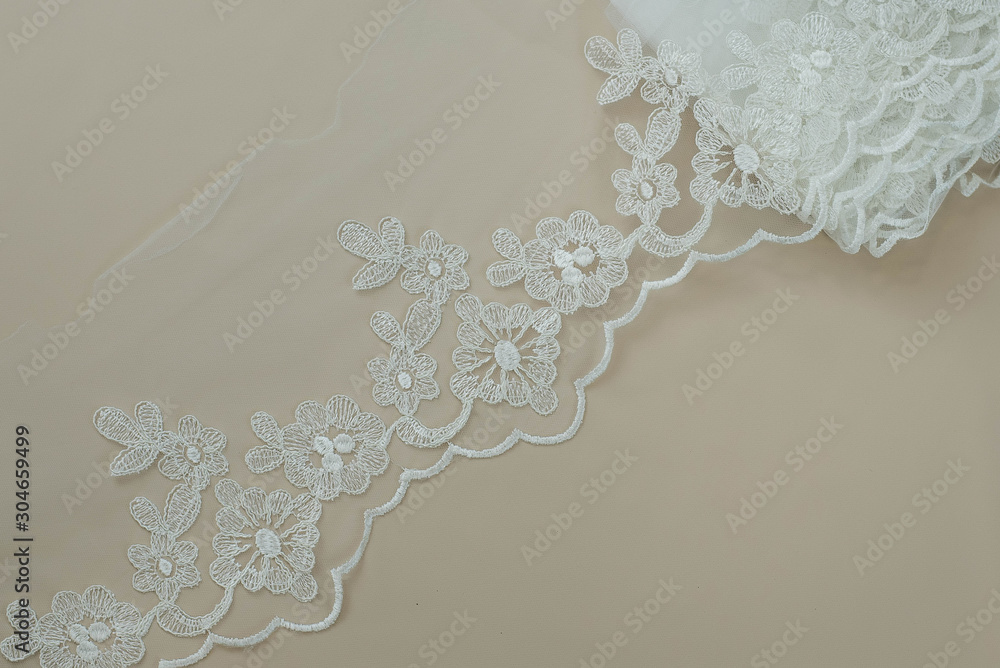 Texture lace fabric. lace on white background studio. thin fabric made of yarn or thread. a background image of ivory-colored lace cloth. White lace on beige background. Texture lace fabric. lace on white background studio. thin fabric made of yarn or thread. a background image of ivory-colored lace cloth. White lace on beige background.