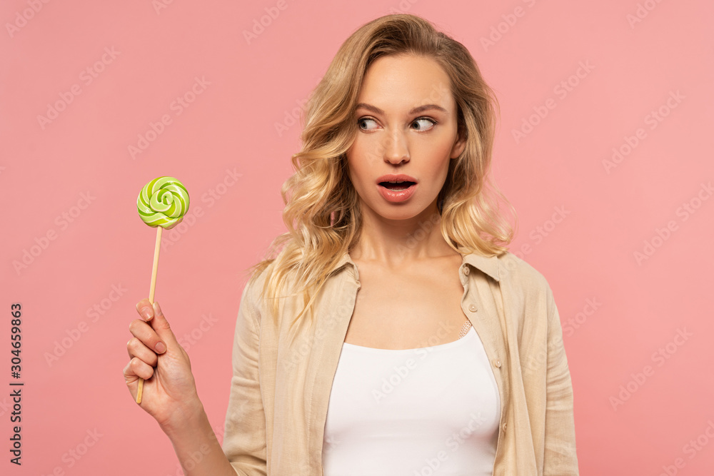 Exited woman looking at lollipop isolated on pink Exited woman looking at lollipop isolated on pink
