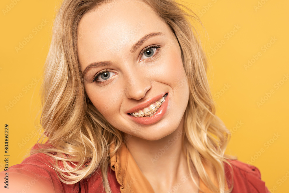 Camera point of view of smiling woman with dental braces taking selfie isolated on yellow Camera point of view of smiling woman with dental braces taking selfie isolated on yellow