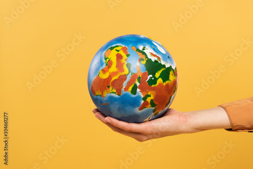 Cropped view of globe in woman hand isolated on yellow