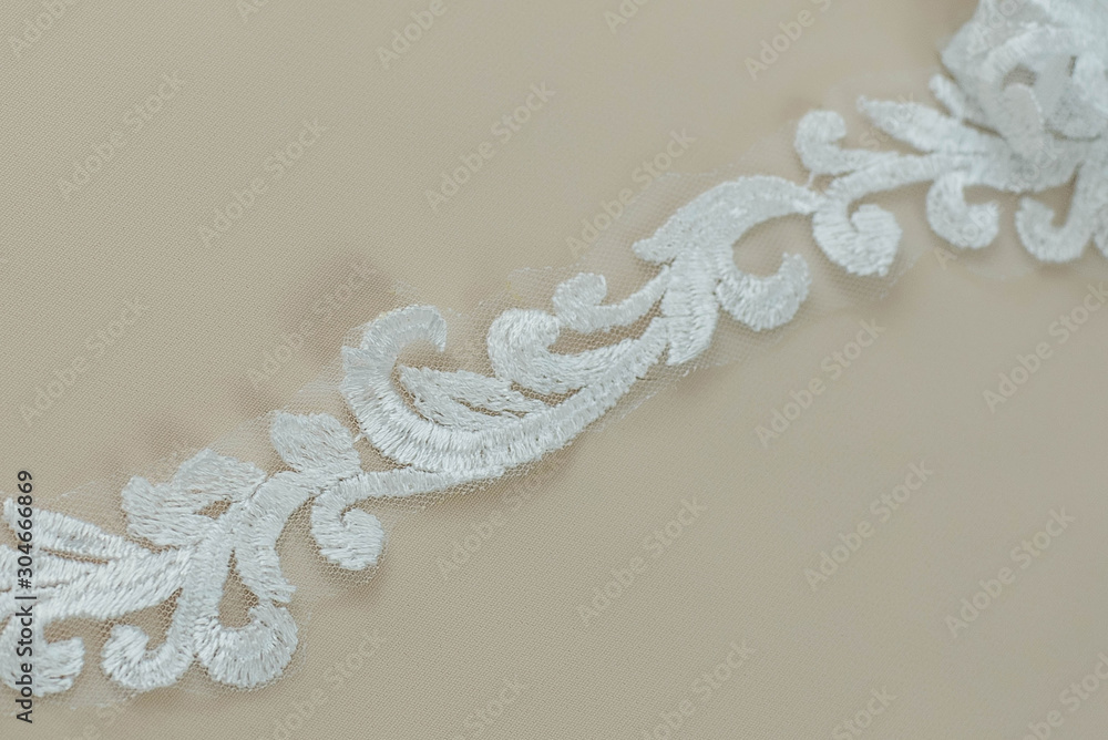 Texture lace fabric. lace on white background studio. thin fabric made of yarn or thread. a background image of ivory-colored lace cloth. White lace on beige background. Texture lace fabric. lace on white background studio. thin fabric made of yarn or thread. a background image of ivory-colored lace cloth. White lace on beige background.