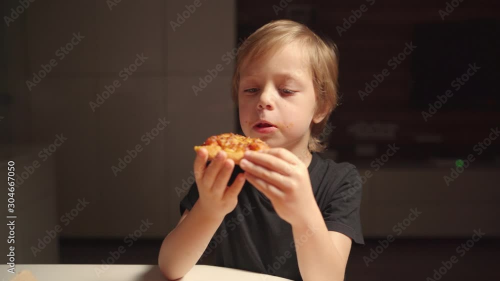 Boy eating pizza at home kitchen late night. Boys at home alone Boy eating pizza at home kitchen late night. Boys at home alone