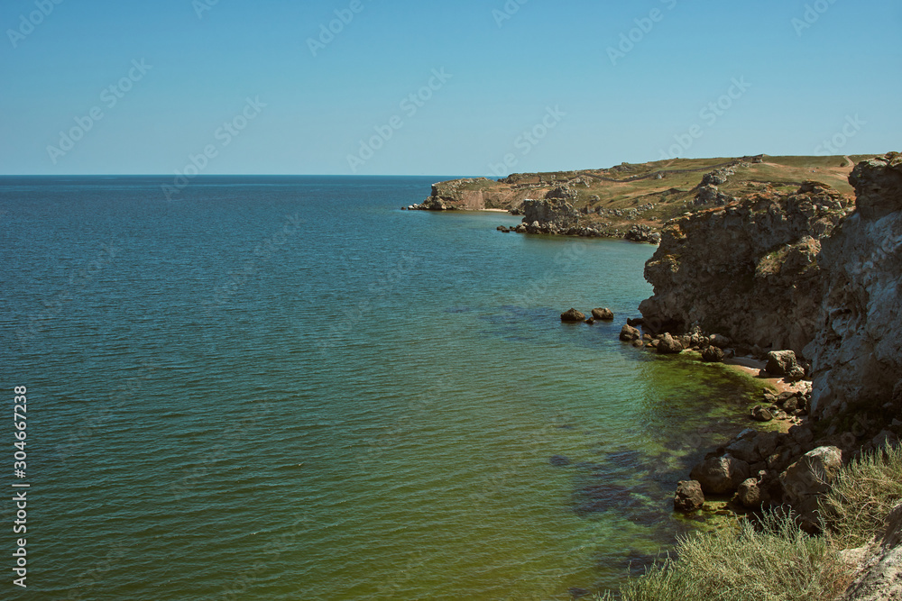 Scenic view of the rugged coastline. Sea coast with high cliffs. Peaked rocks on the seashore