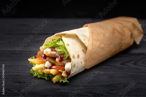 Tasty doner kebabs with fresh salad trimmings and shaved roasted meat served in tortilla wraps on brown paper as a takeaway snack photo