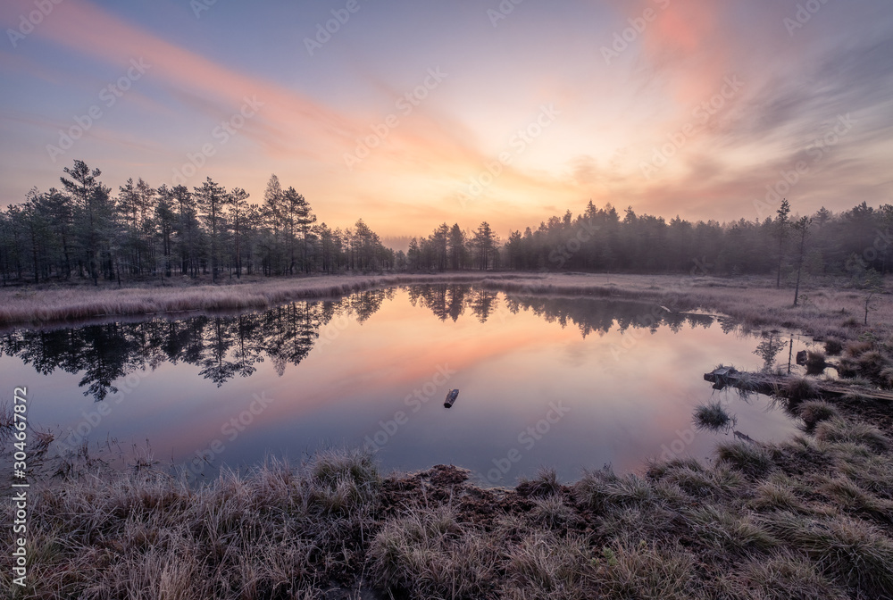 Calmness and cold autumn morning landscape with sunrise, beautiful reflections and peaceful lake in Finland