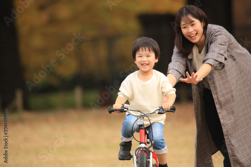 自転車に乗る練習をする親子 © yamasan