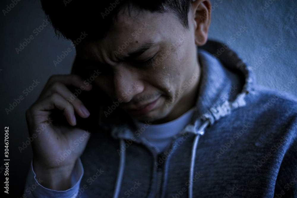 通話しながら涙を流す男性 通話しながら涙を流す男性