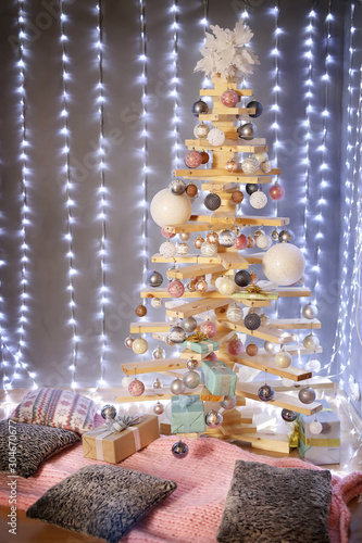 Alternative Christmas tree . the original Christmas tree in the new year of wood boards, decorated with balls, on the background of lights garlands .