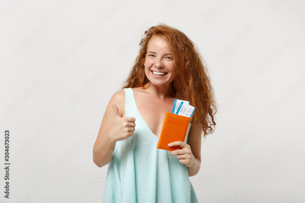 Young smiling redhead woman girl in casual light clothes posing isolated on white background. People lifestyle concept. Mock up copy space. Holding passport, boarding pass, ticket, showing thumb up. Young smiling redhead woman girl in casual light clothes posing isolated on white background. People lifestyle concept. Mock up copy space. Holding passport, boarding pass, ticket, showing thumb up.