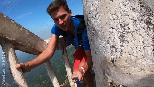 The traveler blogger makes videos for instagram on social networks. He make a dangerous climb to a unique tower 48 meters high located on the Ambuluwawa hill at an altitude of 356 m above sea level.