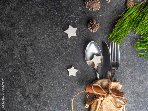 Christmas table place setting, cutlery in burlap bag with festive decorations star, golden bow, pinecone with snow, green branch . Christmas Xmas New Year holiday background