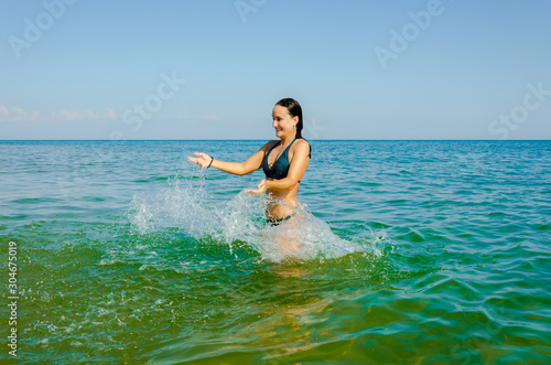 Young girl in swimsuit posing in the sea in summer.