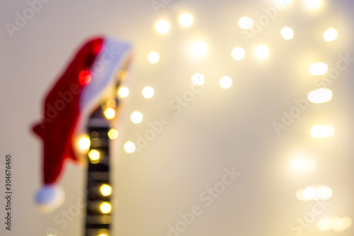 Blurred Acoustic Guitar with red Santa hat and light garland. Christmas music song concept with copyspace for background
