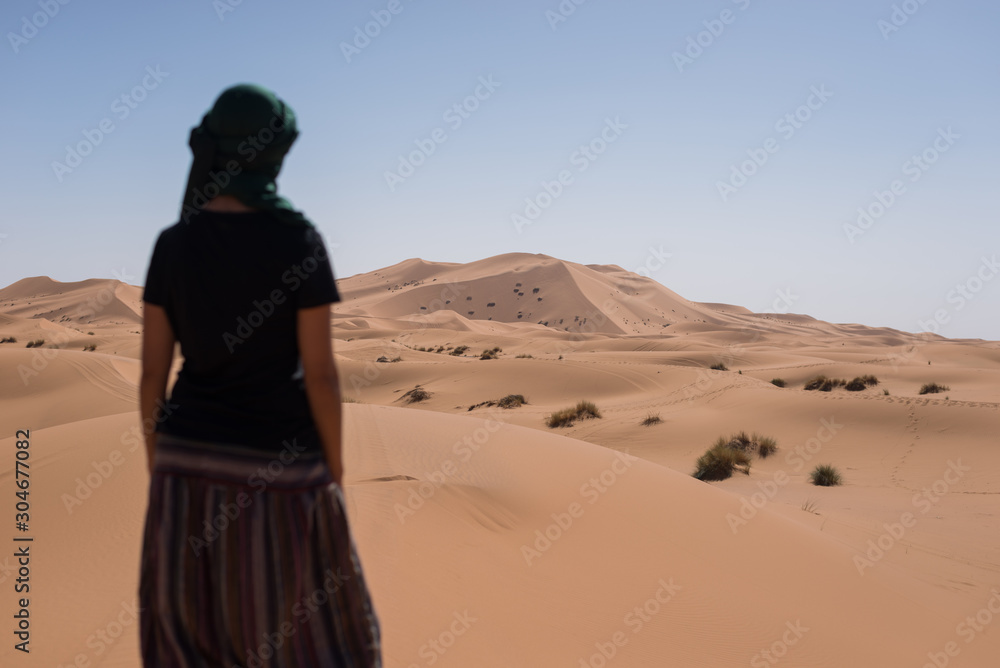 Woman looking at the horizon dunes in the Moroccan Sahara desert. Woman looking at the horizon dunes in the Moroccan Sahara desert.
