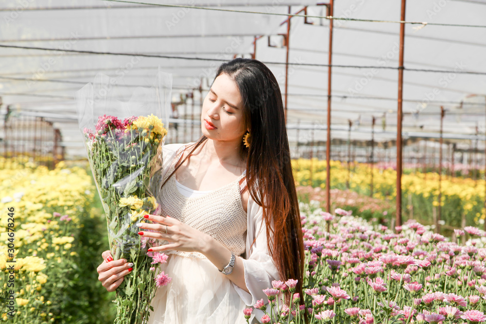 Portrait young beautiful asian woman in white dress relaxing at chrysanthemum flower garden