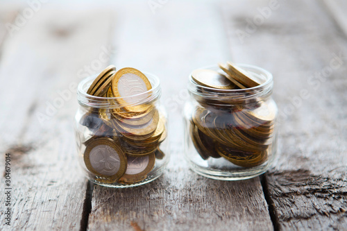 Glass jars with money coins ruble on wooden table. 10 ten ruble coins.