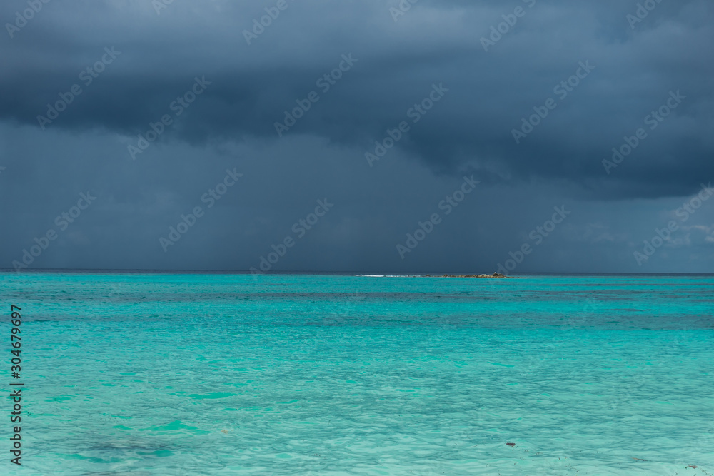 Separate view of a tropical island with turquoise sea, coconut palm trees and blue sky in the Maldives. Indian Ocean Sunset