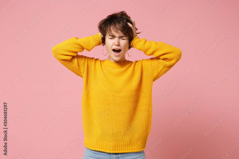 Frustrated young brunette woman girl in yellow sweater posing isolated on pastel pink background. People lifestyle concept. Mock up copy space. Screaming keeping eyes closed, putting hands on head. Frustrated young brunette woman girl in yellow sweater posing isolated on pastel pink background. People lifestyle concept. Mock up copy space. Screaming keeping eyes closed, putting hands on head.