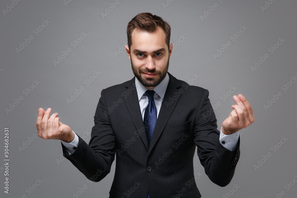 Young business man in classic suit shirt tie posing isolated on grey background. Achievement career wealth business concept. Mock up copy space. Rubbing fingers showing cash gesture asking for money. Young business man in classic suit shirt tie posing isolated on grey background. Achievement career wealth business concept. Mock up copy space. Rubbing fingers showing cash gesture asking for money.