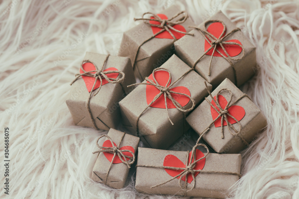 Set of gift boxes wrapped in craft paper and tie hemp string. With cardboard hearts. White fur background. New year. Christmas mood. Set of gift boxes wrapped in craft paper and tie hemp string. With cardboard hearts. White fur background. New year. Christmas mood.