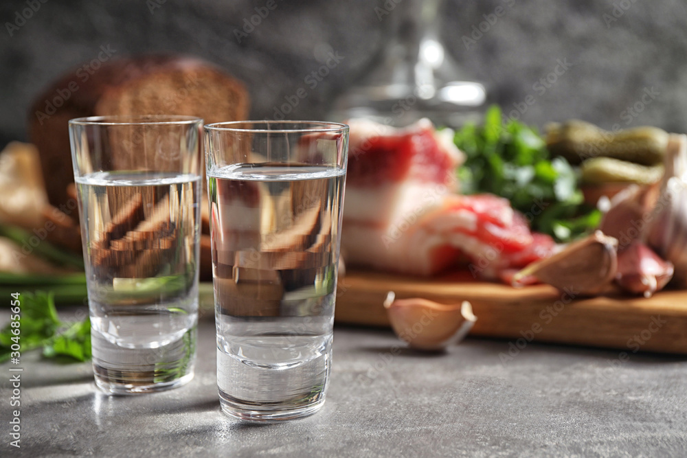 Cold Russian vodka with snacks on grey table, closeup Cold Russian vodka with snacks on grey table, closeup