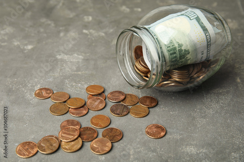 Overturned glass jar with money on grey stone table