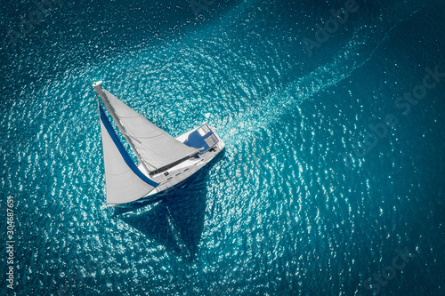Regatta sailing ship yachts with white sails at opened sea. Aerial view of sailboat in windy condition © ValentinValkov